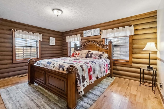 675 Indian Cave Subdivision Rd, Monticello, KY 42633 - bedroom featuring wood finished floors, log walls, and a textured ceiling