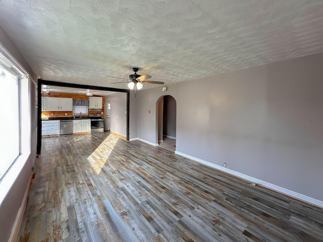 247 Mt Sterling Ave, Flemingsburg, KY 41041 - unfurnished living room with arched walkways, dark wood-style floors, a textured ceiling, and ceiling fan