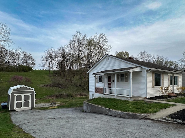 247 Mt Sterling Ave, Flemingsburg, KY 41041 - view of front of property featuring a front yard, covered porch, a chimney, an outbuilding, and a storage shed