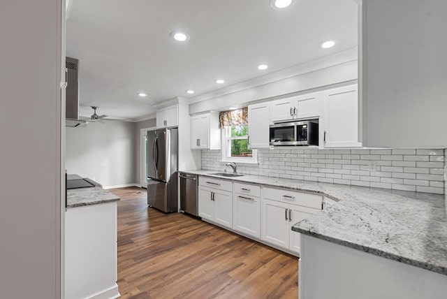 kitchen with appliances with stainless steel finishes, a sink, ornamental molding, white cabinetry, and backsplash