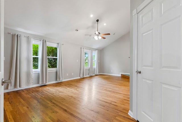 spare room with a ceiling fan, healthy amount of natural light, light wood-style flooring, vaulted ceiling, and baseboards