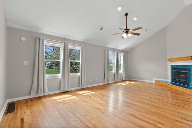 unfurnished living room featuring ceiling fan, light wood-type flooring, lofted ceiling, baseboards, and a tiled fireplace