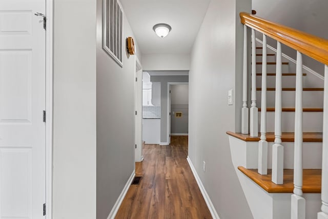 hallway with wood finished floors, baseboards, and stairway