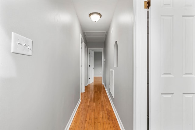 hall with attic access, light wood-style flooring, and baseboards