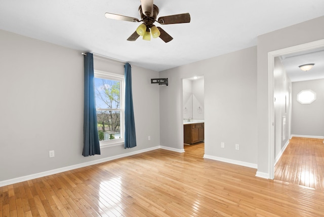 spare room featuring light wood-style flooring, a ceiling fan, and baseboards
