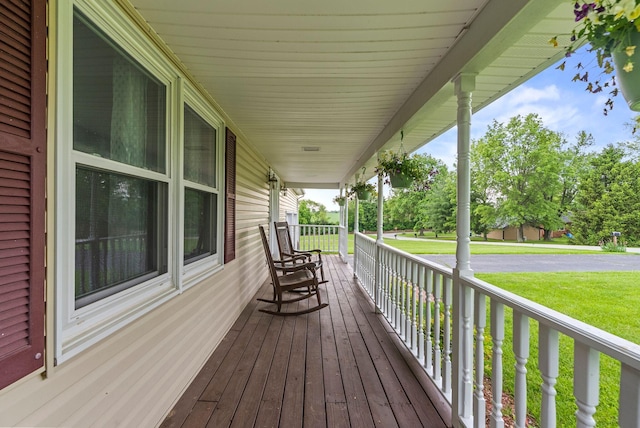 wooden terrace featuring a porch and a lawn