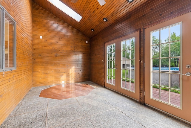 entryway featuring lofted ceiling, a skylight, wood ceiling, french doors, and wood walls