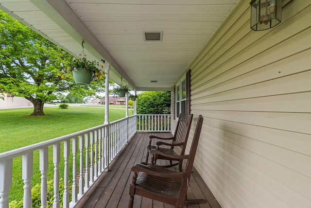 wooden deck featuring a porch and a yard