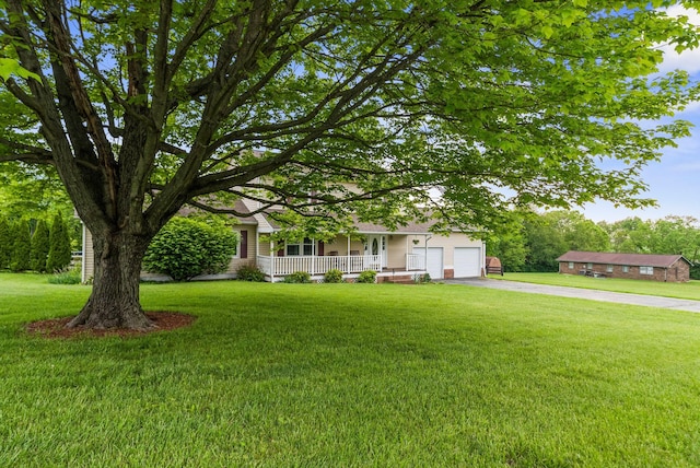 view of front of property with a porch, driveway, a front lawn, and an attached garage