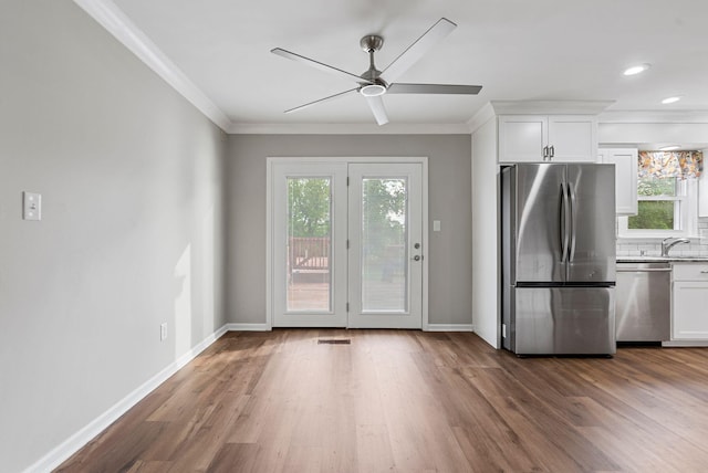 doorway with crown molding, healthy amount of natural light, dark wood-style flooring, a ceiling fan, and recessed lighting