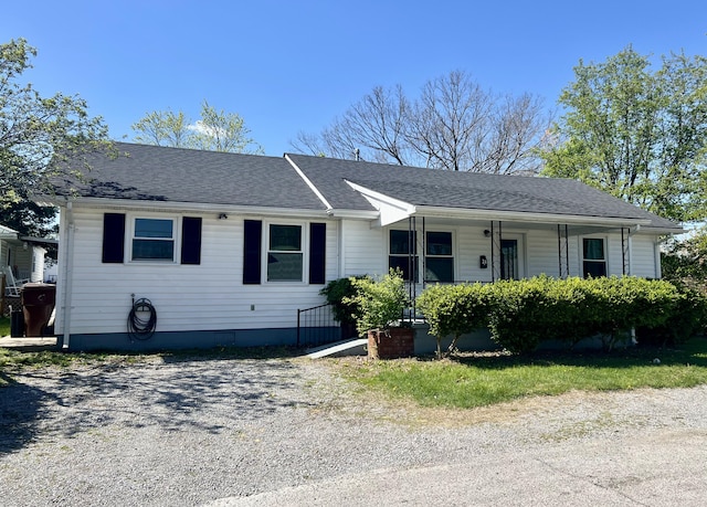 ranch-style home with roof with shingles and a porch