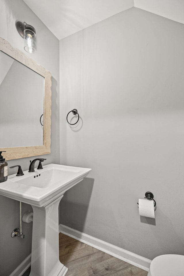 bathroom featuring toilet, wood finished floors, a sink, and baseboards