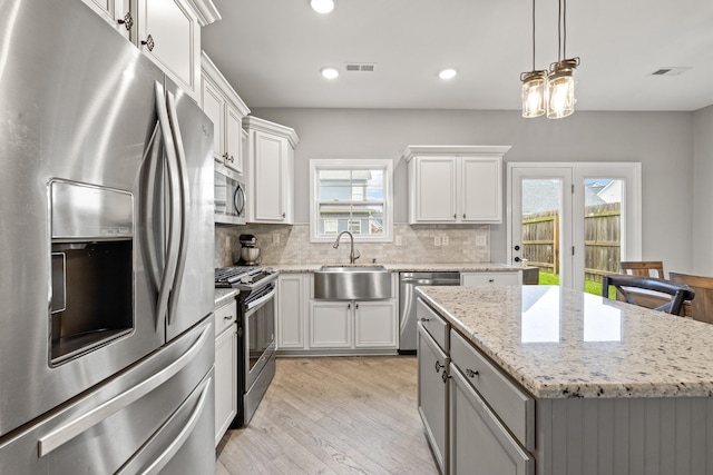 kitchen with visible vents, a sink, stainless steel appliances, light wood-style flooring, and decorative backsplash