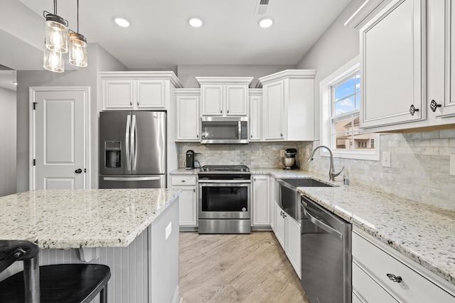 kitchen featuring light wood-type flooring, decorative backsplash, white cabinets, and stainless steel appliances