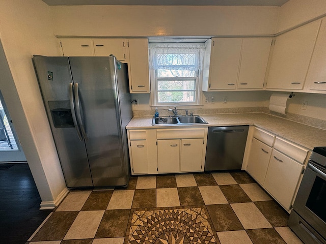 kitchen featuring light countertops, dark floors, a sink, white cabinets, and appliances with stainless steel finishes