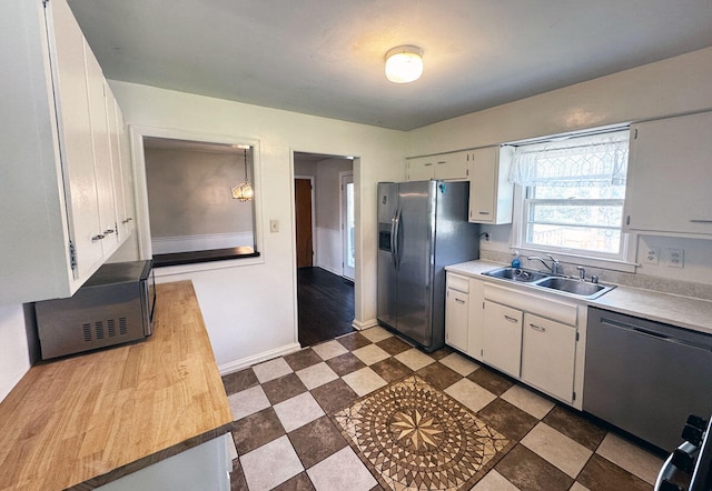 kitchen featuring light countertops, a sink, white cabinetry, stainless steel appliances, and dark floors