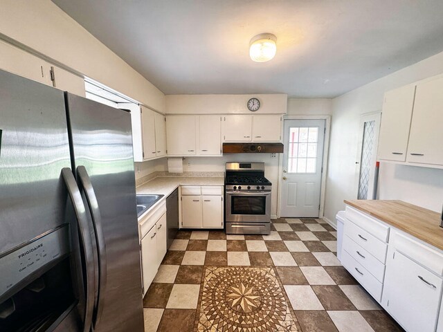 kitchen featuring white cabinetry, light countertops, under cabinet range hood, dark floors, and appliances with stainless steel finishes