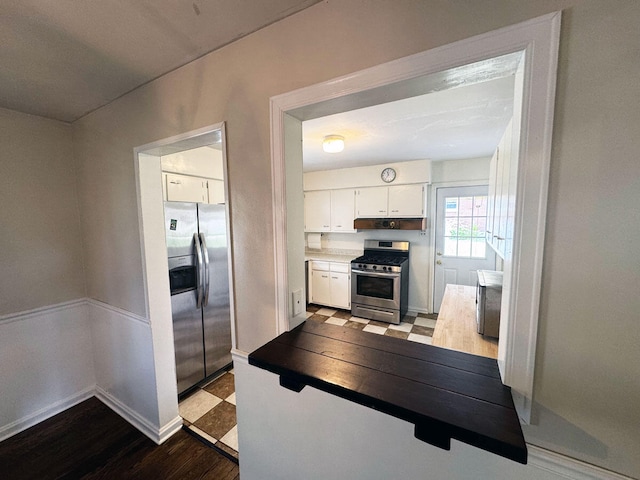 kitchen with baseboards, white cabinets, wood finished floors, and appliances with stainless steel finishes
