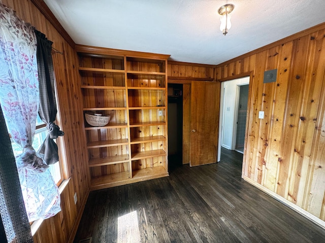 unfurnished bedroom featuring dark wood finished floors, wooden walls, and crown molding