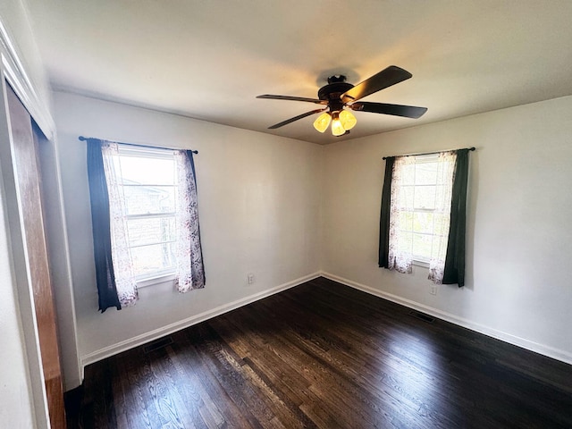 empty room with a ceiling fan, visible vents, baseboards, and dark wood finished floors