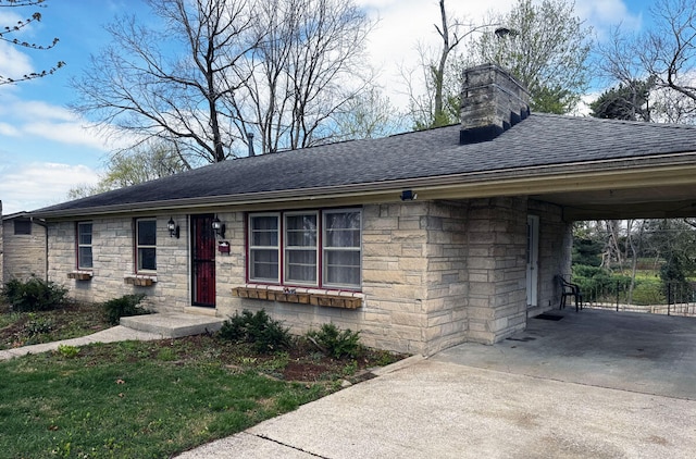 ranch-style home featuring stone siding, a chimney, concrete driveway, an attached carport, and roof with shingles