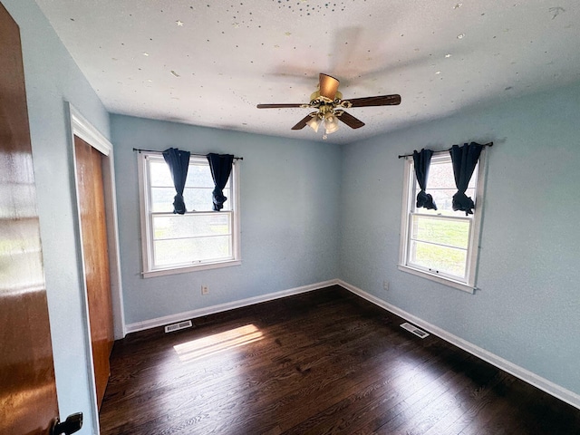 empty room with baseboards, visible vents, wood finished floors, and a ceiling fan