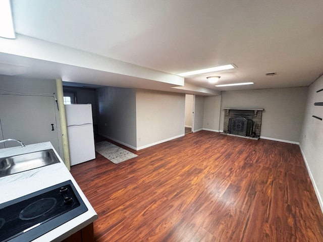 kitchen with baseboards, wood finished floors, a sink, and freestanding refrigerator