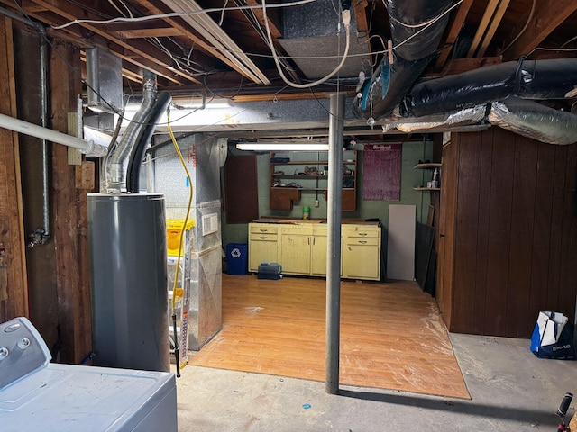 unfinished below grade area with water heater, washer / clothes dryer, and wood walls