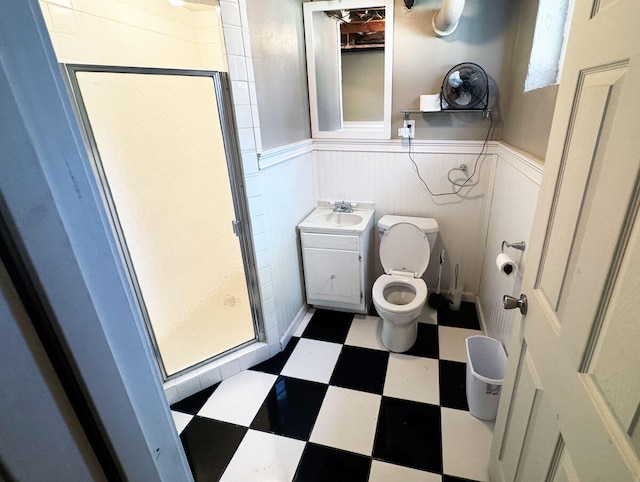 bathroom featuring a stall shower, tile patterned floors, a sink, and a wainscoted wall