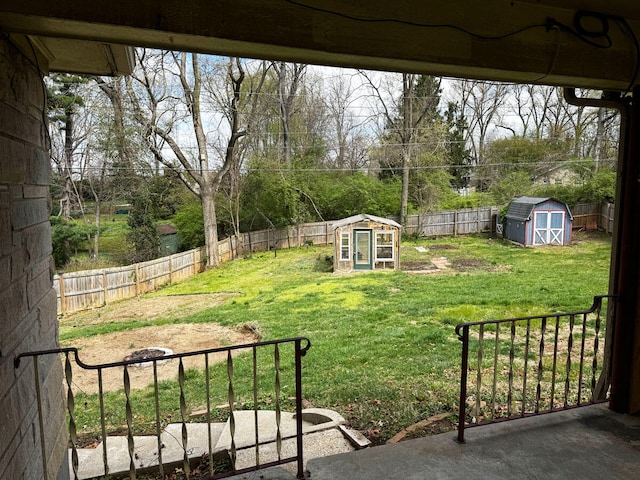 view of yard with a fenced backyard, an outbuilding, and a storage shed