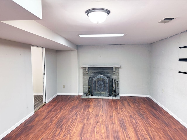 unfurnished living room with visible vents, baseboards, a fireplace, and wood finished floors