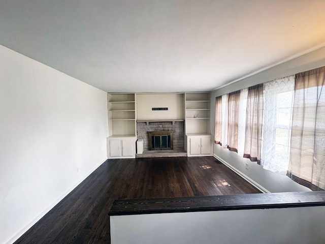 unfurnished living room featuring a brick fireplace, visible vents, baseboards, and wood finished floors