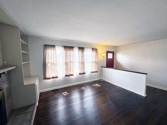 unfurnished living room featuring baseboards, wood finished floors, and a brick fireplace