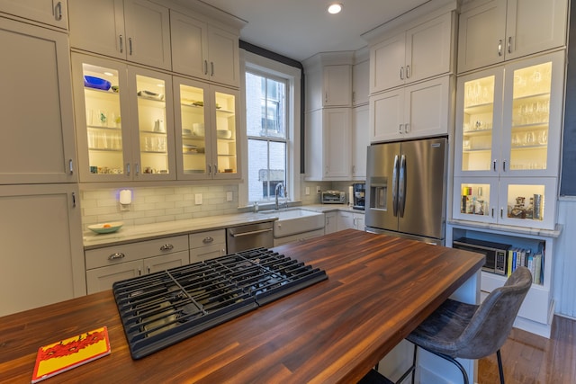 261 N Broadway, Lexington, KY 40507 - kitchen featuring wooden counters, appliances with stainless steel finishes, a sink, glass insert cabinets, and tasteful backsplash