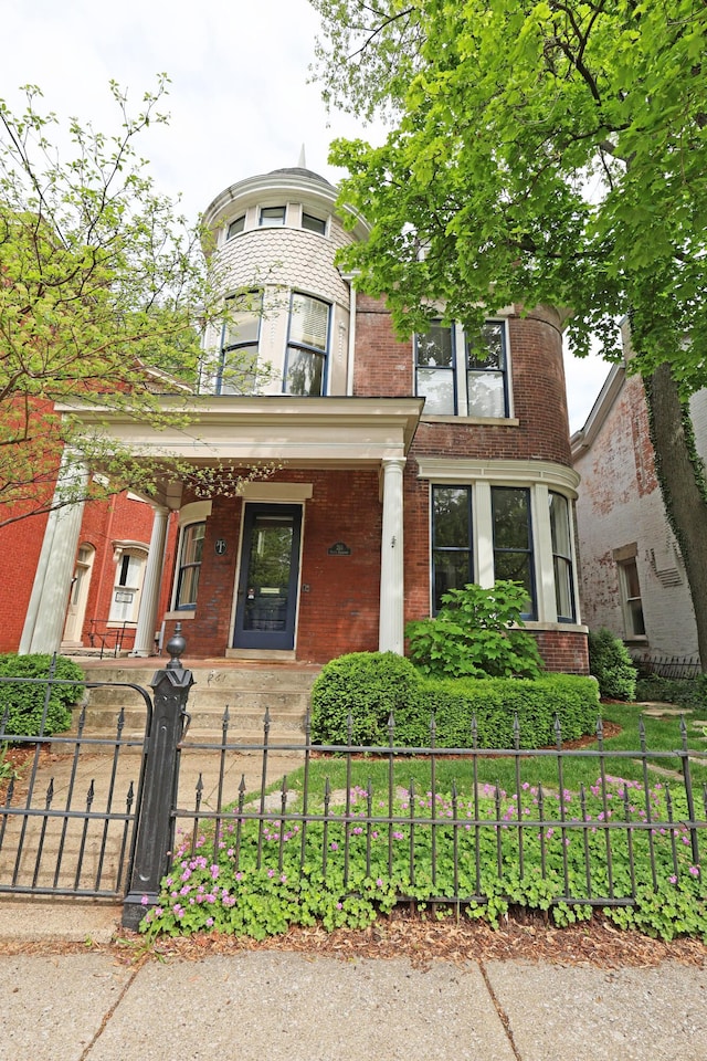 261 N Broadway, Lexington, KY 40507 - victorian house with covered porch, brick siding, a fenced front yard, and a gate