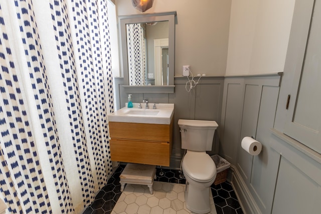 261 N Broadway, Lexington, KY 40507 - bathroom featuring toilet, a decorative wall, vanity, a wainscoted wall, and tile patterned flooring