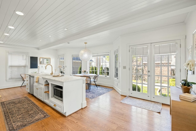 kitchen with a sink, french doors, appliances with stainless steel finishes, light wood-style flooring, and decorative light fixtures