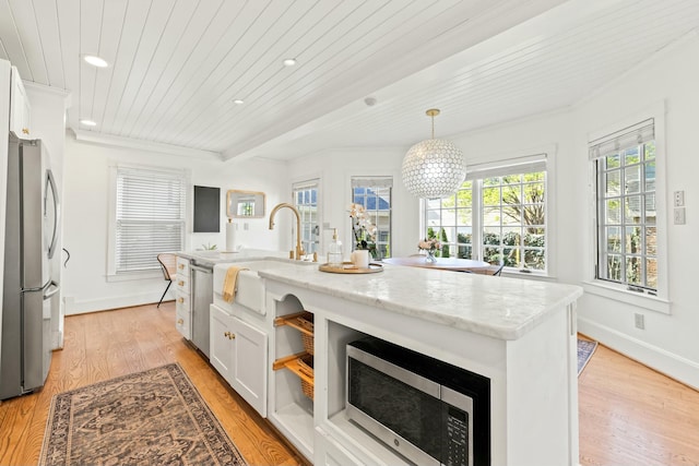 kitchen with hanging light fixtures, a sink, light wood finished floors, white cabinets, and appliances with stainless steel finishes