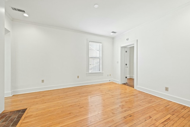 empty room featuring baseboards, visible vents, crown molding, and wood-type flooring