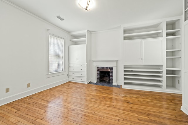 unfurnished living room featuring visible vents, baseboards, a fireplace, built in shelves, and light wood-style floors