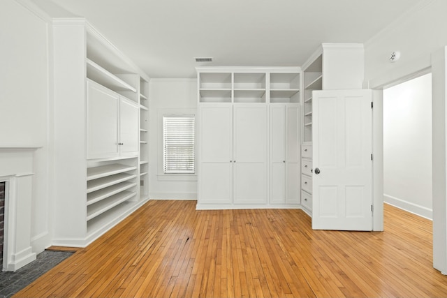 walk in closet featuring visible vents, light wood-type flooring, and a brick fireplace