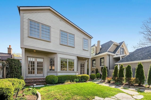 view of front facade featuring a front lawn, brick siding, entry steps, and french doors
