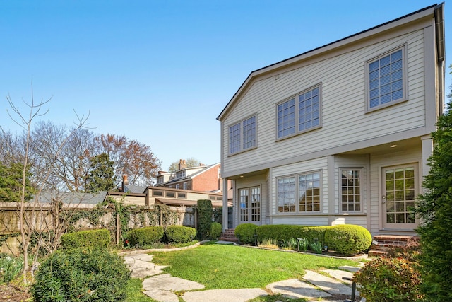 rear view of house featuring a lawn, fence, and entry steps