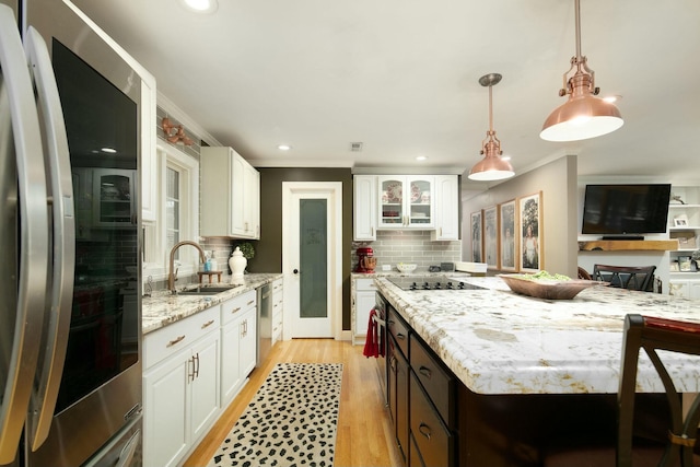 kitchen with stainless steel appliances, white cabinetry, a sink, and crown molding