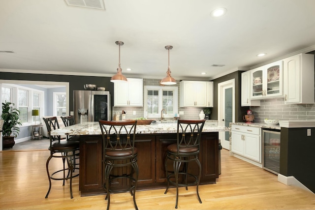 kitchen featuring visible vents, stainless steel fridge, light wood-style floors, wine cooler, and white cabinetry