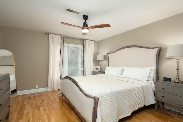 bedroom with visible vents, baseboards, arched walkways, ceiling fan, and light wood-type flooring