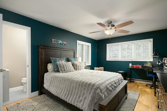 bedroom featuring ensuite bathroom, light wood-type flooring, baseboards, and ceiling fan