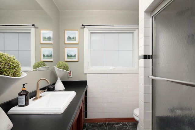 bathroom with toilet, an enclosed shower, tile walls, and vanity