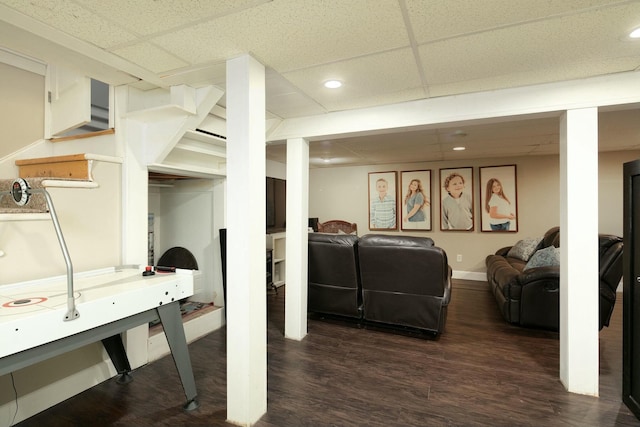 finished below grade area with baseboards, dark wood-style floors, stairway, recessed lighting, and a drop ceiling
