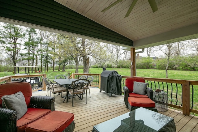 deck featuring outdoor dining space, a ceiling fan, a lawn, and area for grilling